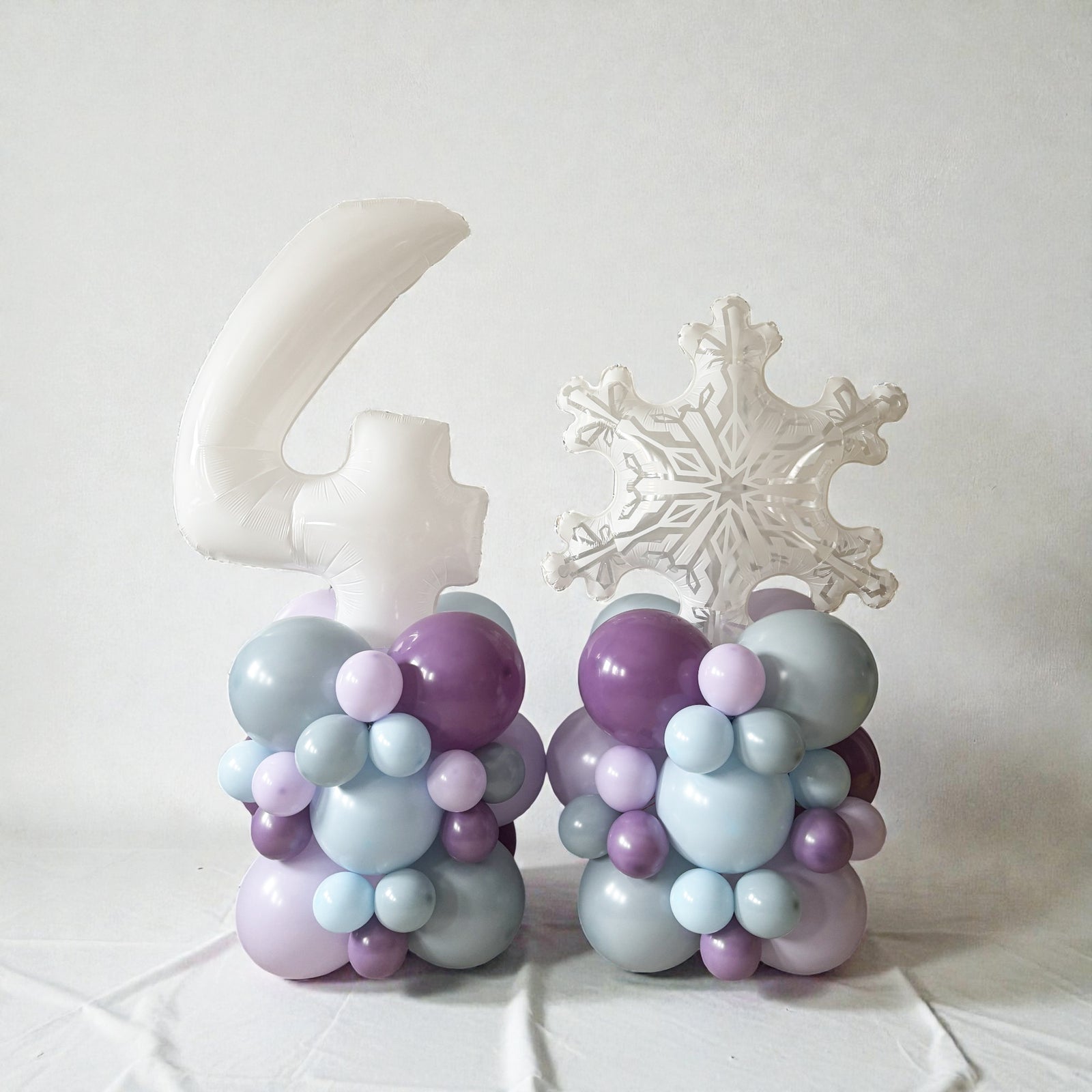 Decorative balloon sculptures shaped like a number '4' and a snowflake on a white background