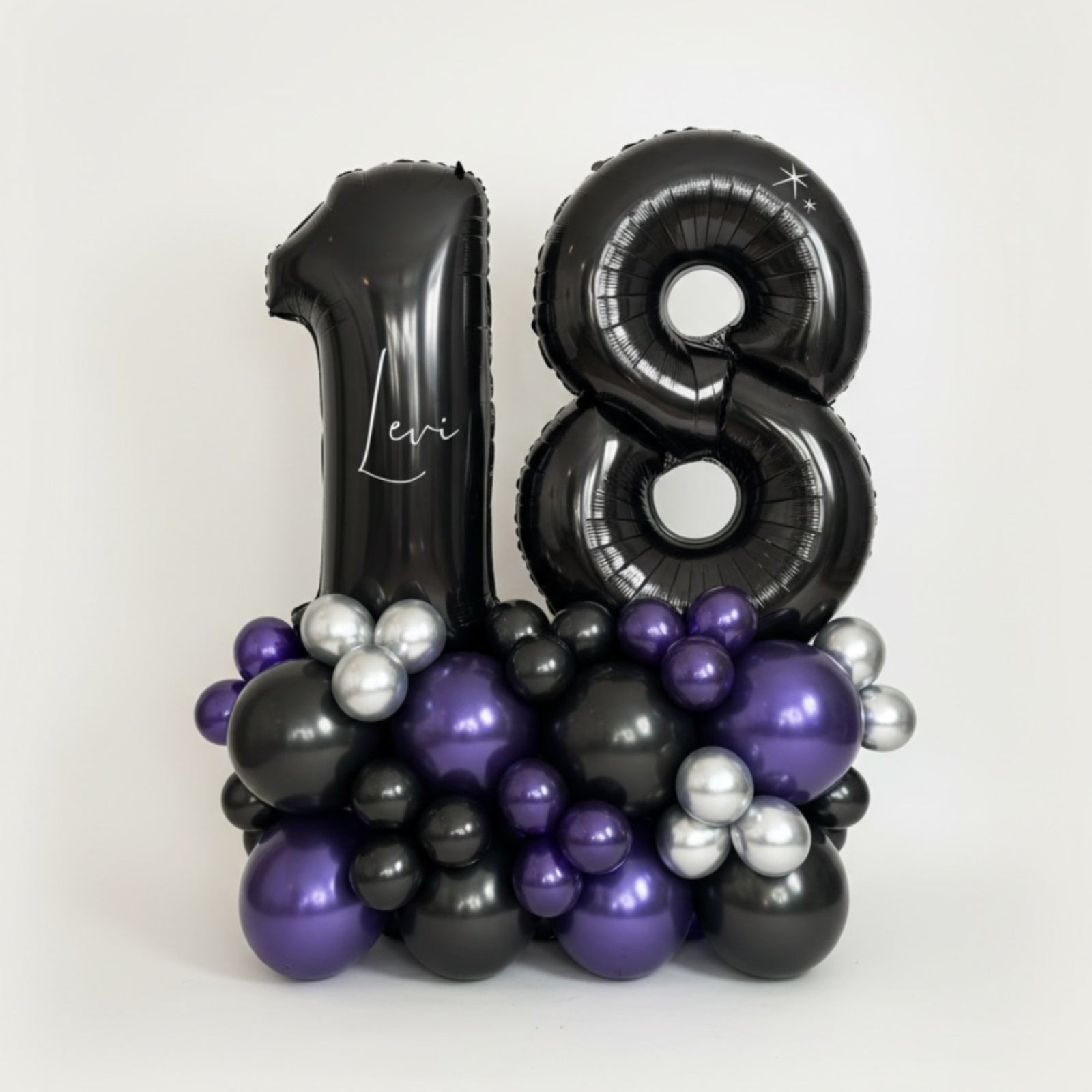 Black, purple, and silver balloon arrangement with 'Levi' on a white background